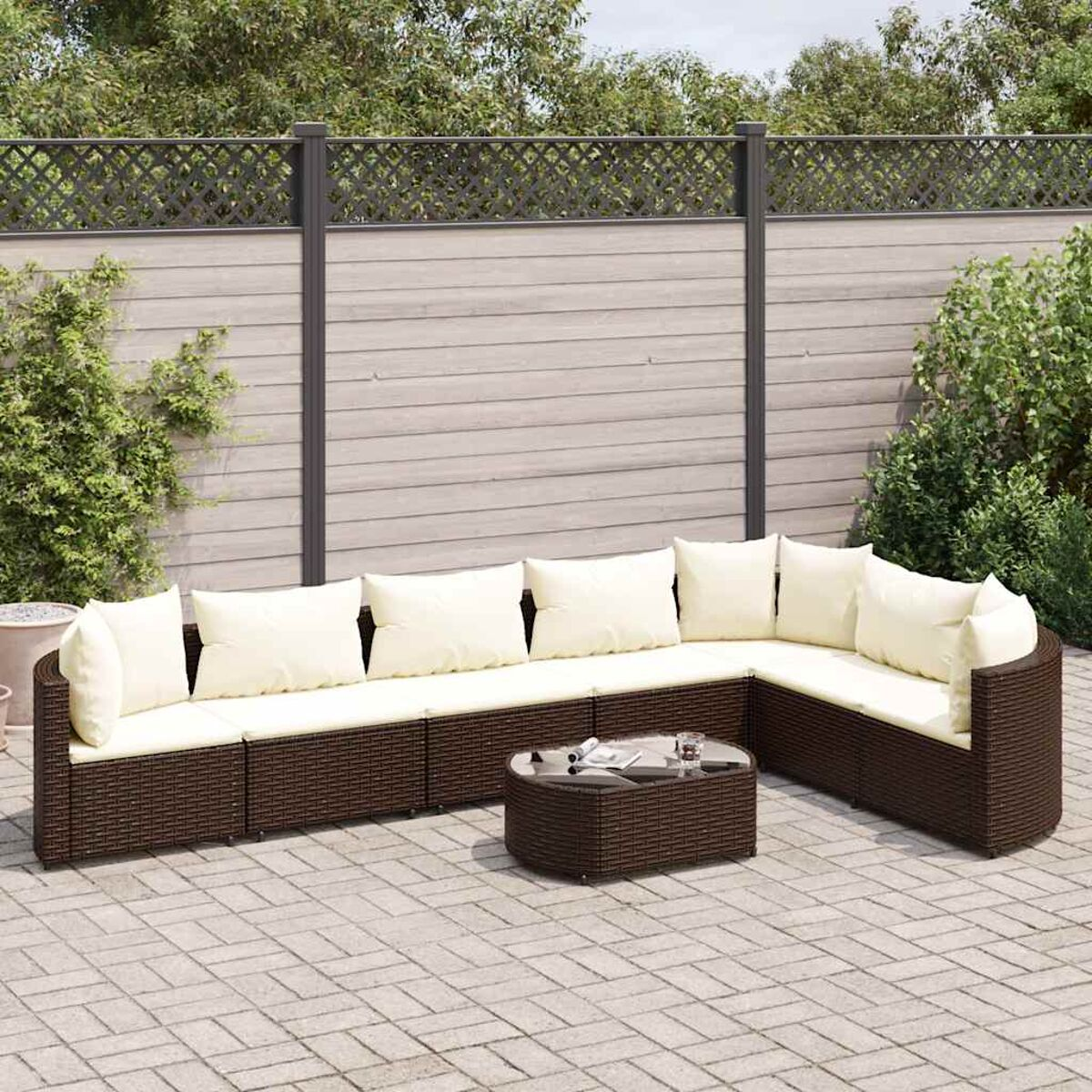 Braunes Geflecht-Gartenmöbel-Set. Sofa und Tisch mit cremefarbenen Kissen.