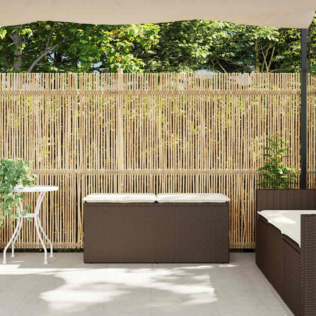 Scena del patio con una recinzione di bambù, una panca contenitore marrone e un tavolino bianco.