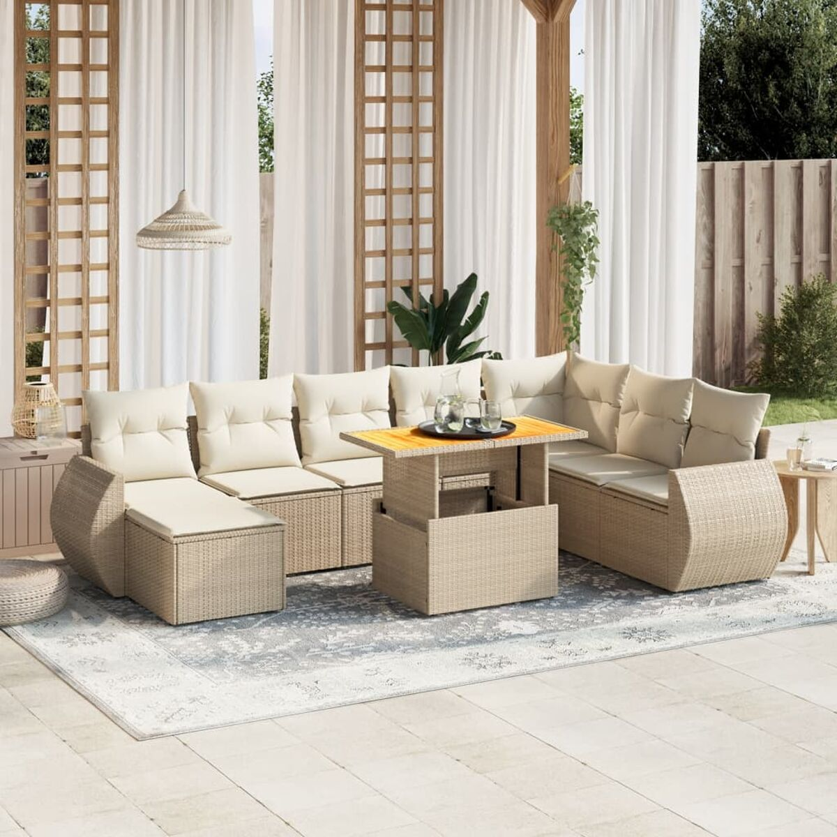 Set patio in vimini beige con tavolo elevabile, cuscini bianchi, su un tappeto fantasia.