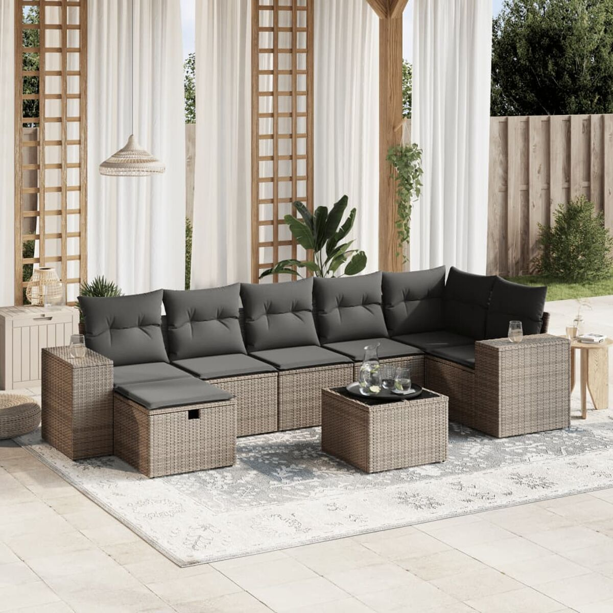Graues Rattan-Ecksofa mit schwarzen Kissen und einem Holztisch. Getränke stehen auf dem Tisch. Teppich.
