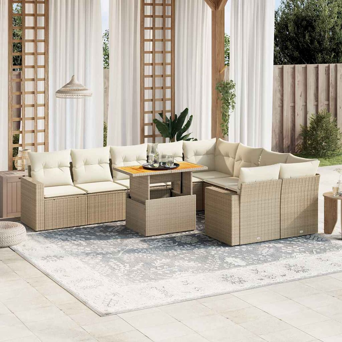 Divano componibile beige da esterno con tavolo elevabile. Tende bianche e tappeto sullo sfondo.