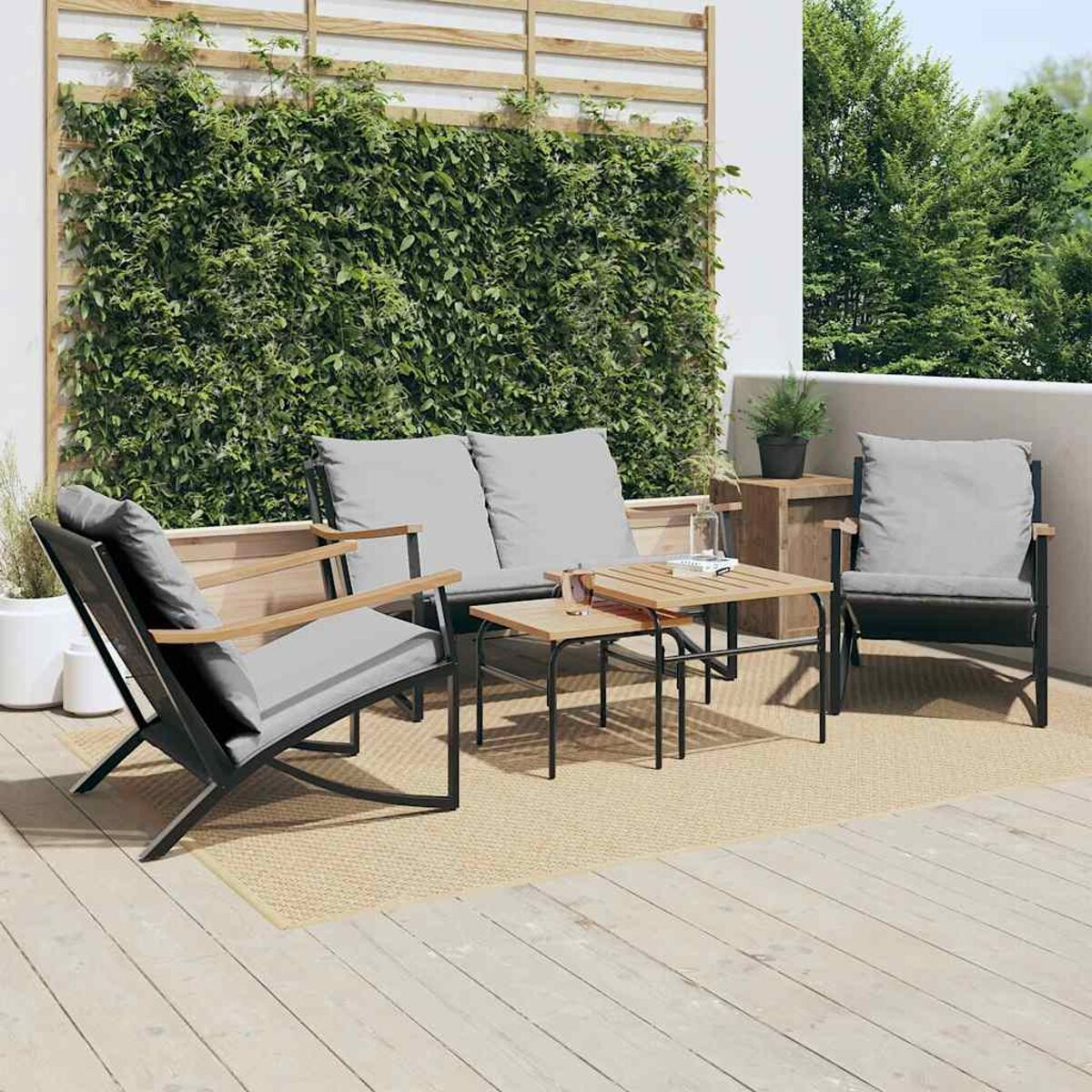 Sitzbereich im Freien mit schwarzen Metallstühlen, einem Sofa und einem Couchtisch aus Holz.