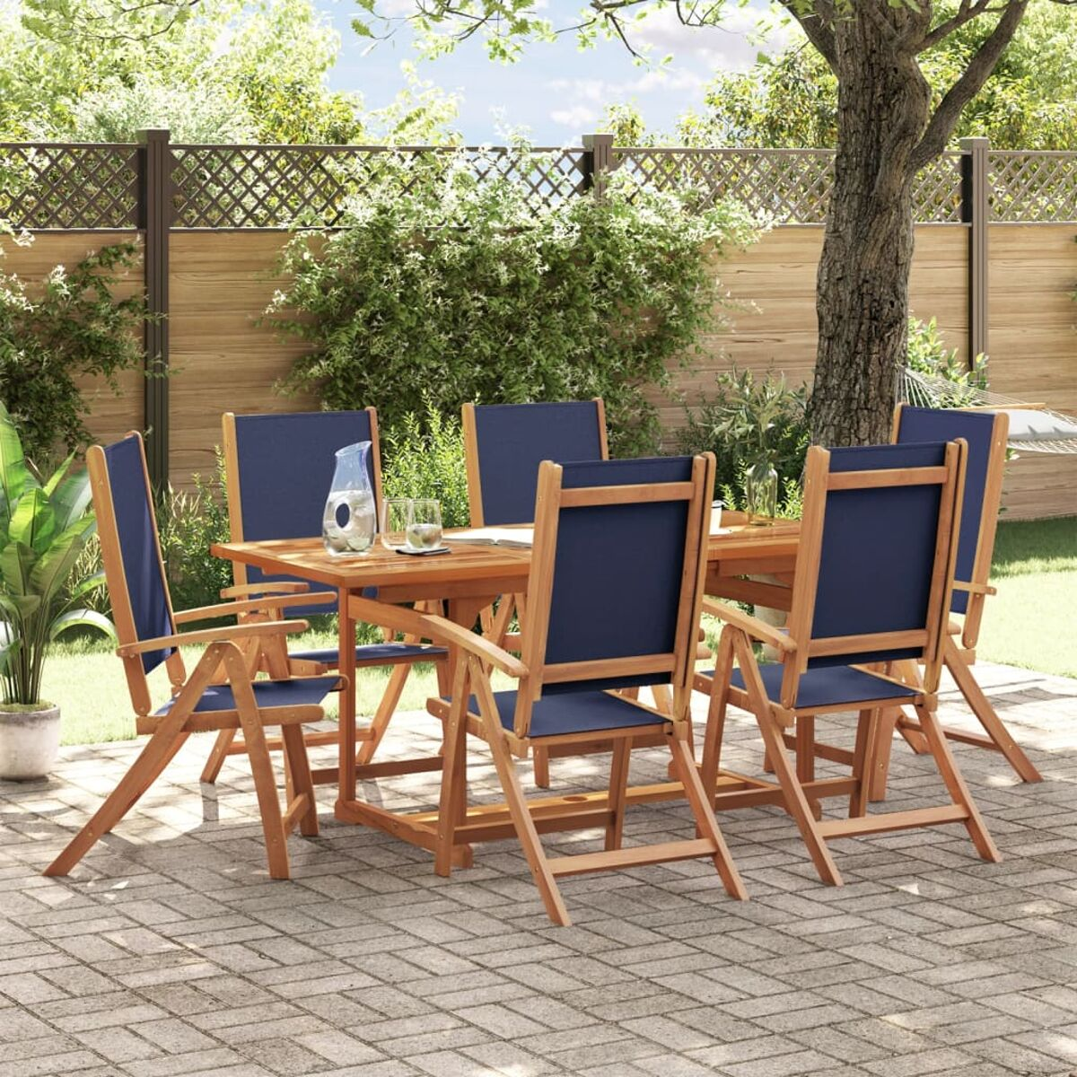 Tavolo in legno con sei sedie con seduta blu in un giardino. Brocca d'acqua.