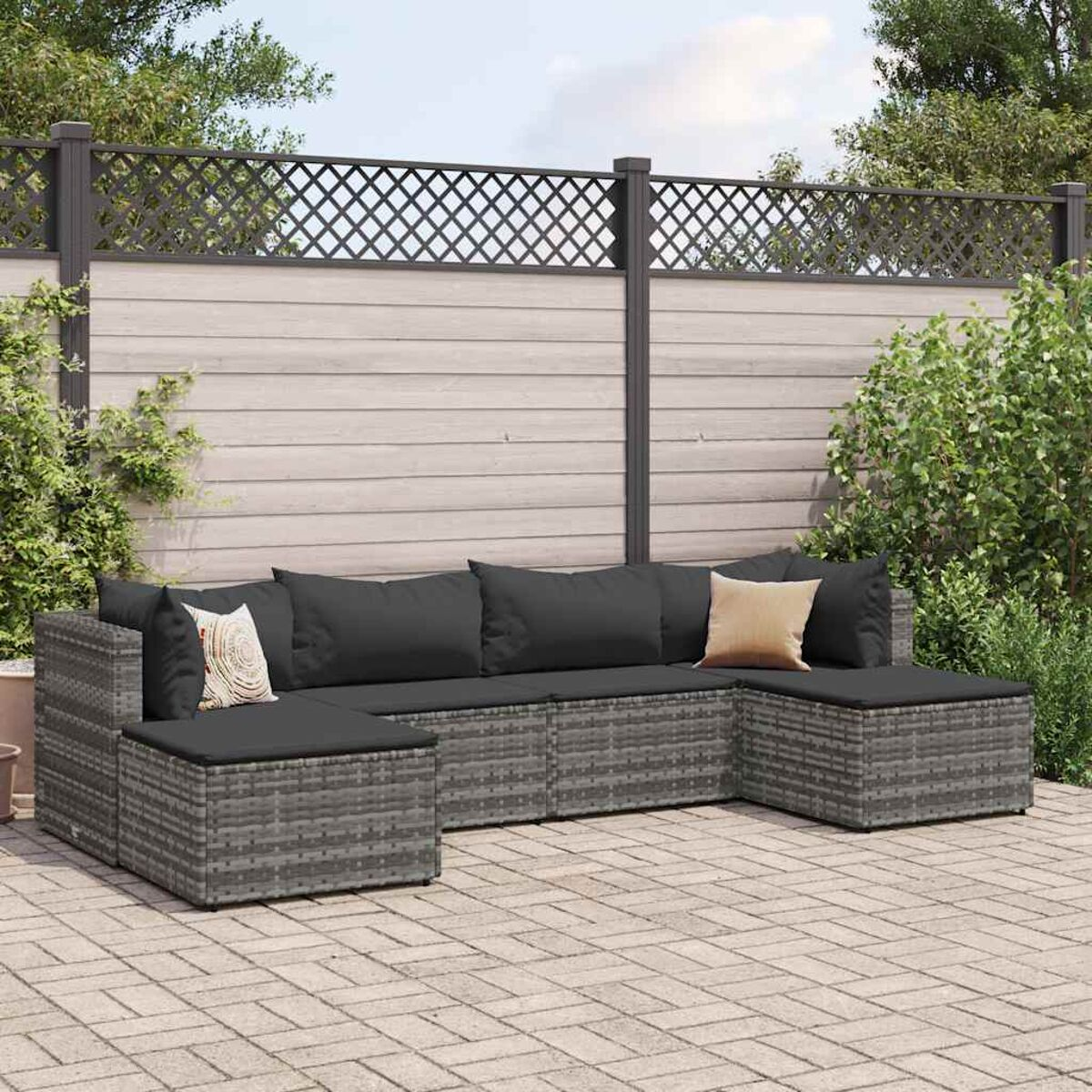 Set patio esterno con mobili in vimini grigio, cuscini e patio in mattoni.