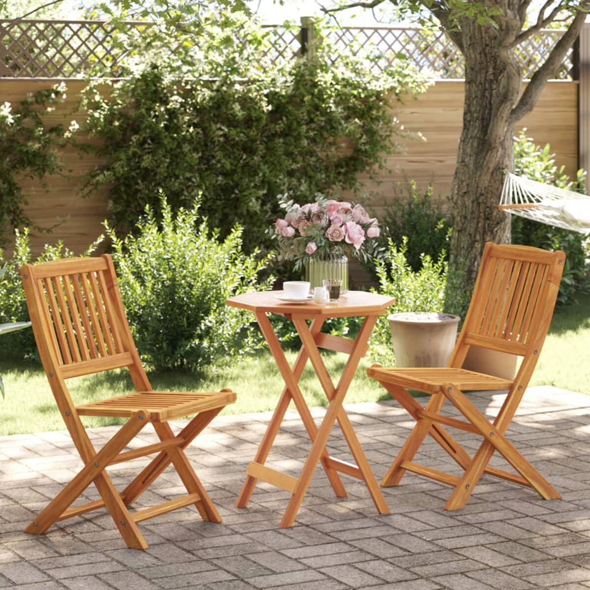 Gartensitzgruppe mit zwei Holzstühlen und einem kleinen Tisch mit Blumen.
