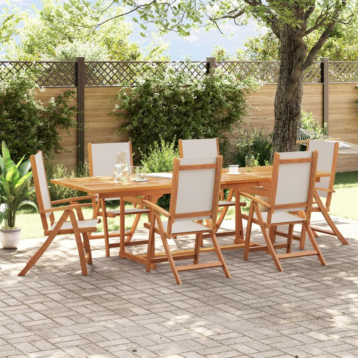Juego de mesa y sillas de madera en jardín. La mesa tiene una jarra y vasos.
