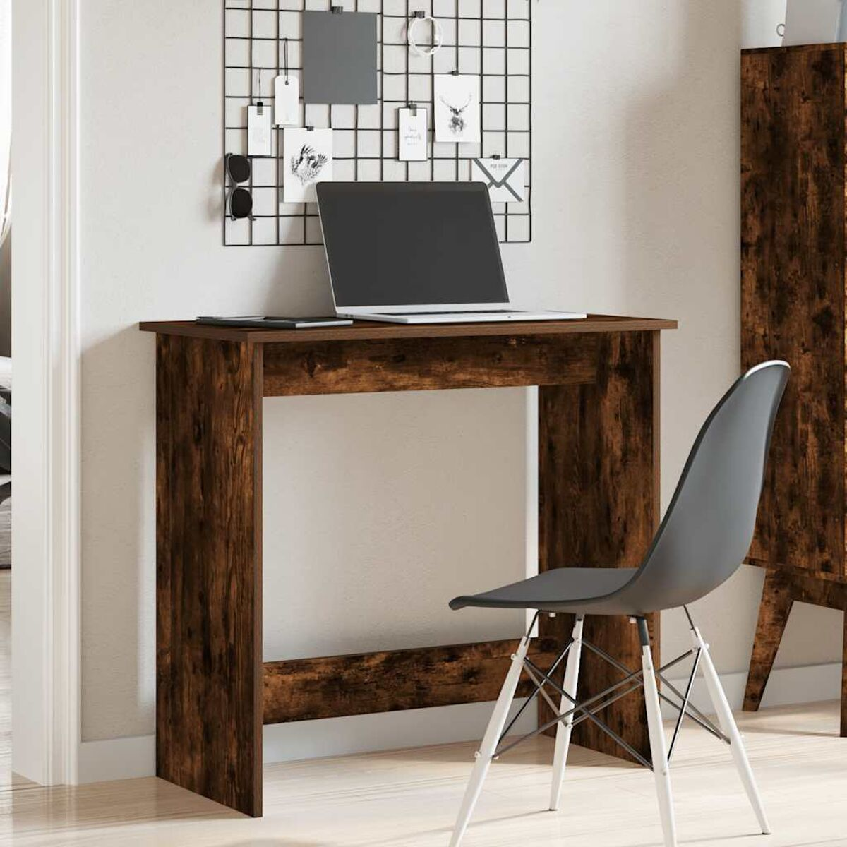 Eine Home-Office-Einrichtung. Ein Schreibtisch, ein Stuhl, ein Laptop und eine Wandtafel für Notizen und Deko.