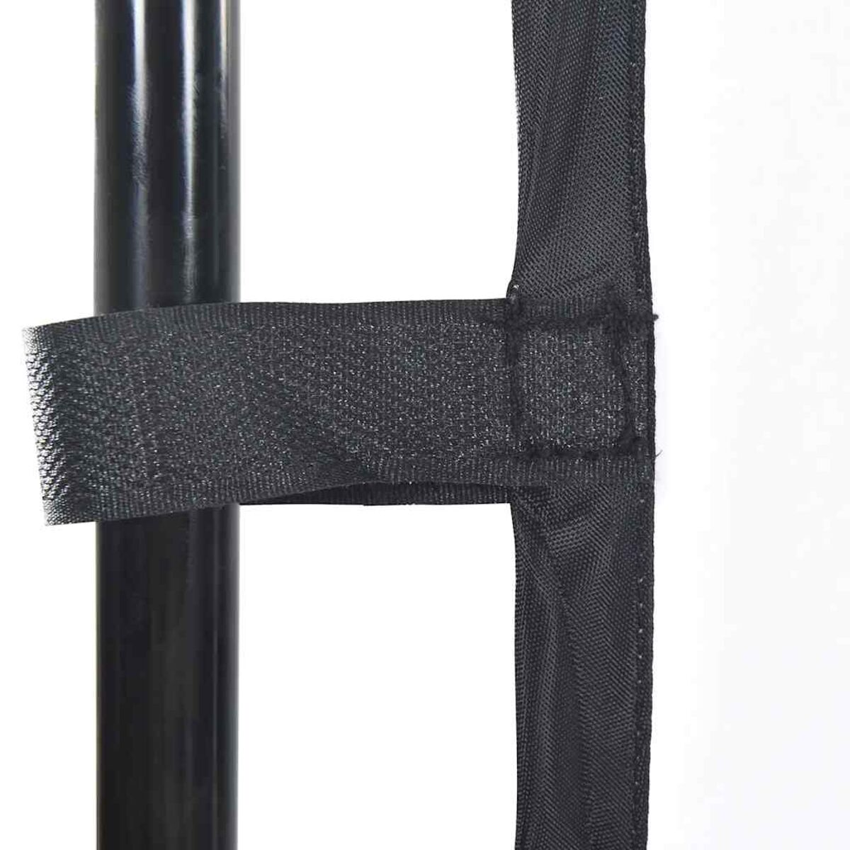 Nahaufnahme von schwarzen Stoffriemen an einem Metallpfosten. Die Riemen werden mit Klettverschluss gehalten.