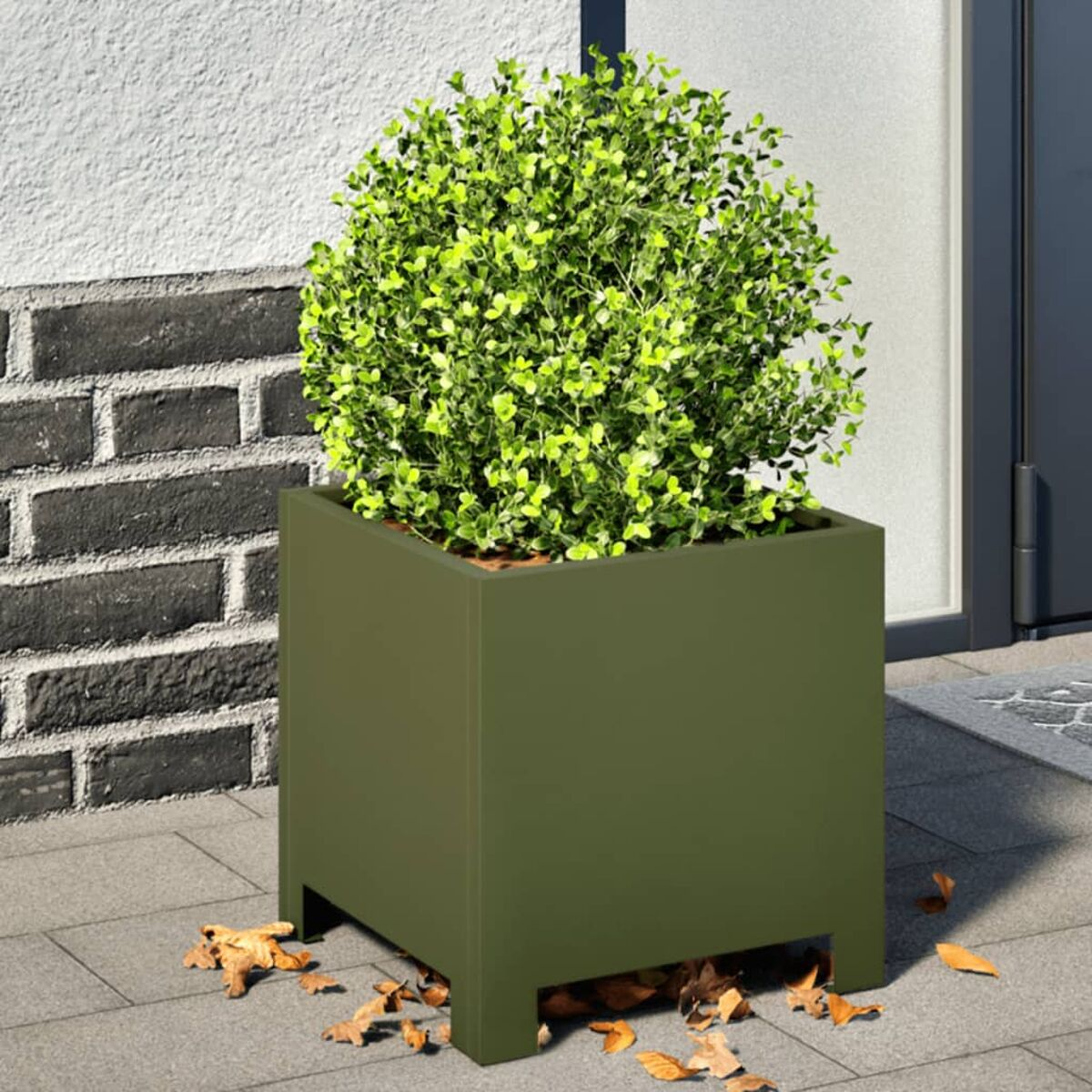 Vaso quadrato verde con un cespuglio verde. È su un patio.