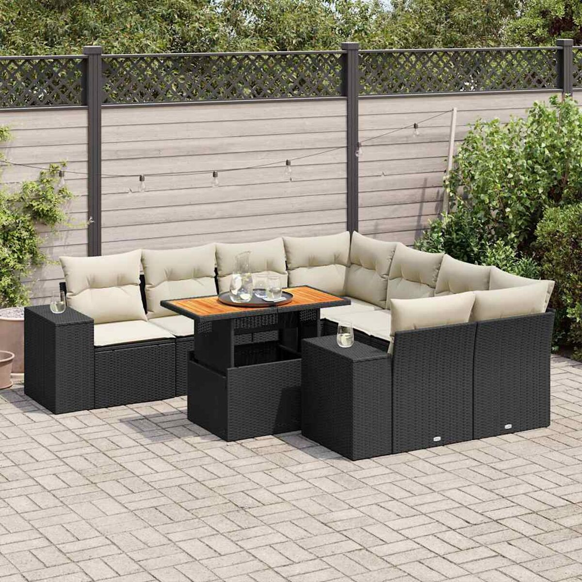 Set di mobili da esterno in vimini nero su un patio, include tavolo e sedute con cuscini.