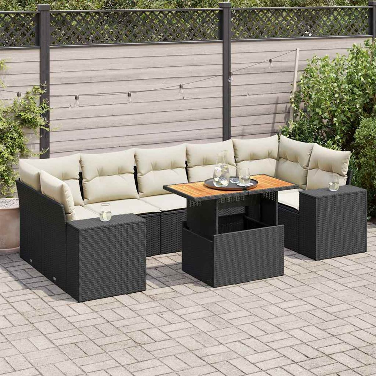 Divano angolare in vimini nero con cuscini color crema e tavolo in legno sul patio.