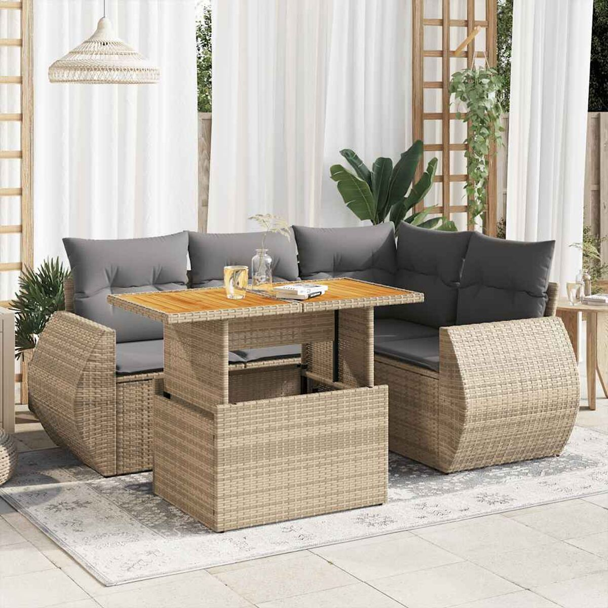 Set da patio all'aperto con un tavolo e due divani. Design in stile vimini con cuscini grigi. Tende bianche.