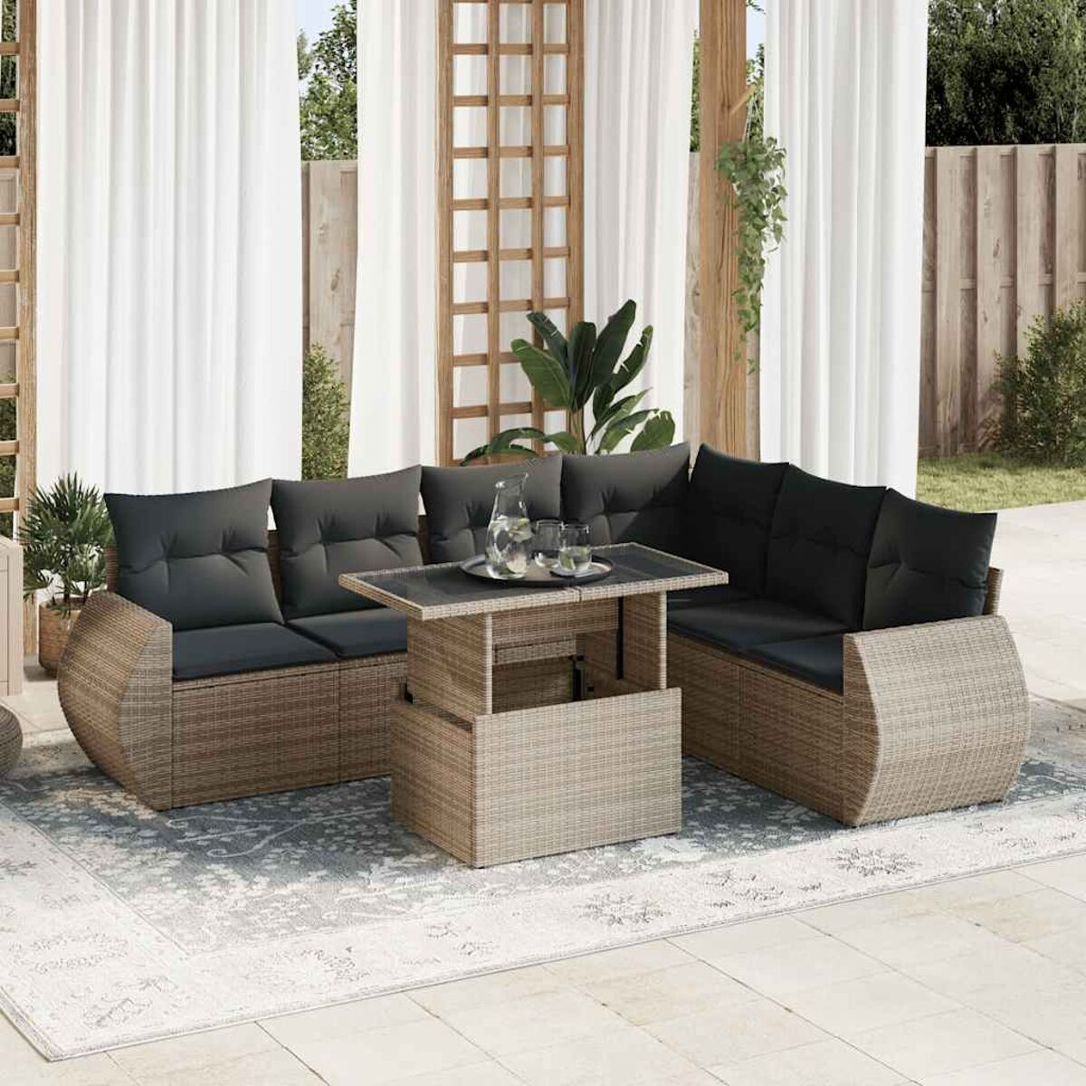 Set patio con cuscini grigi e tavolo. Mobili in vimini con tende sullo sfondo.