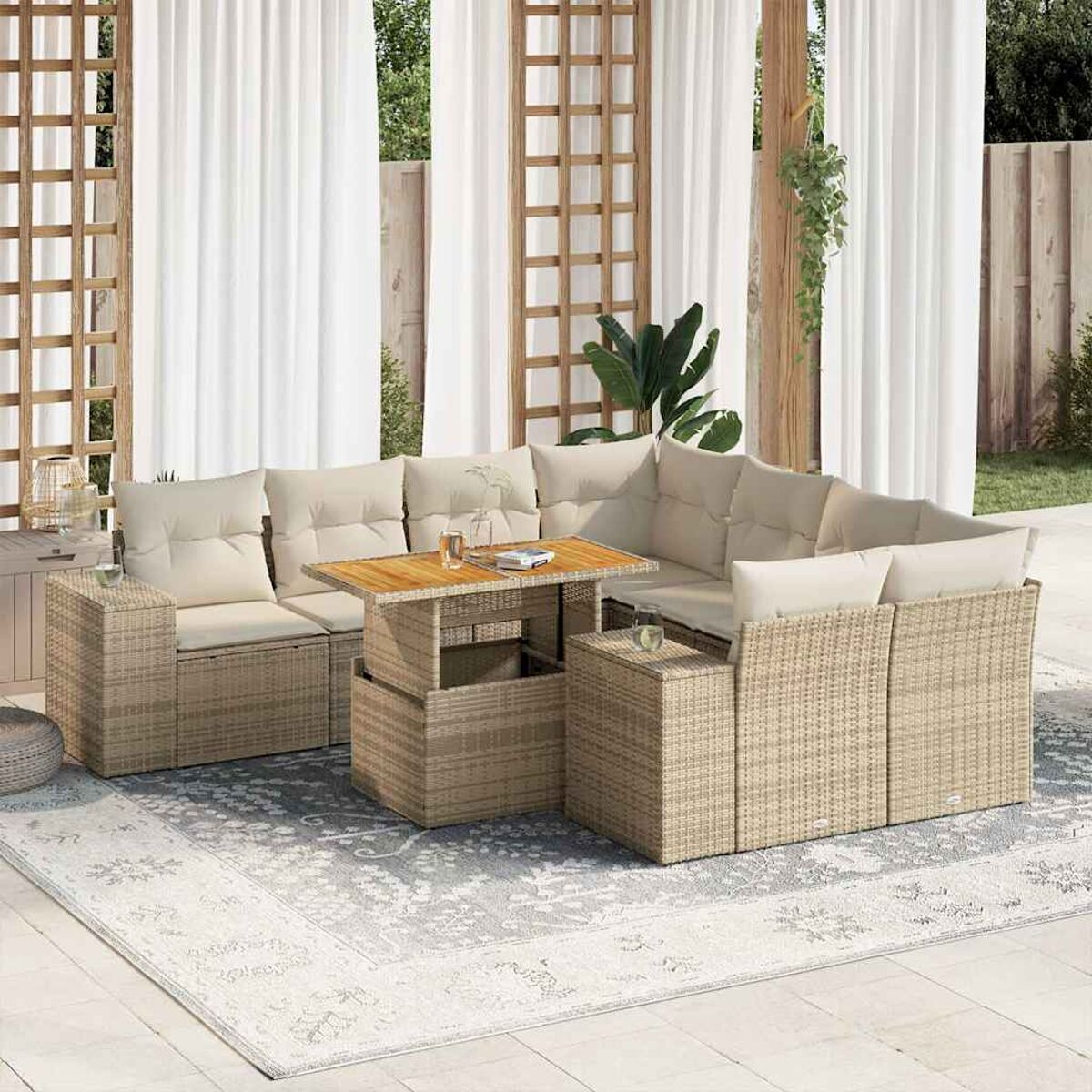 Divano angolare beige in vimini con tavolo in legno, bicchieri e bevande. Tende bianche e piante sullo sfondo.