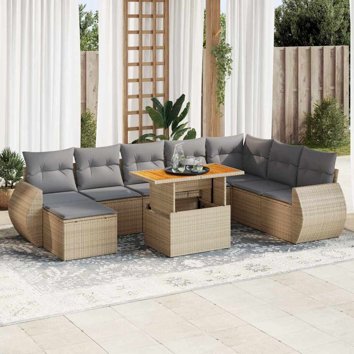 Divano angolare in vimini beige con cuscini grigi, tavolo in legno su tappeto fantasia.
