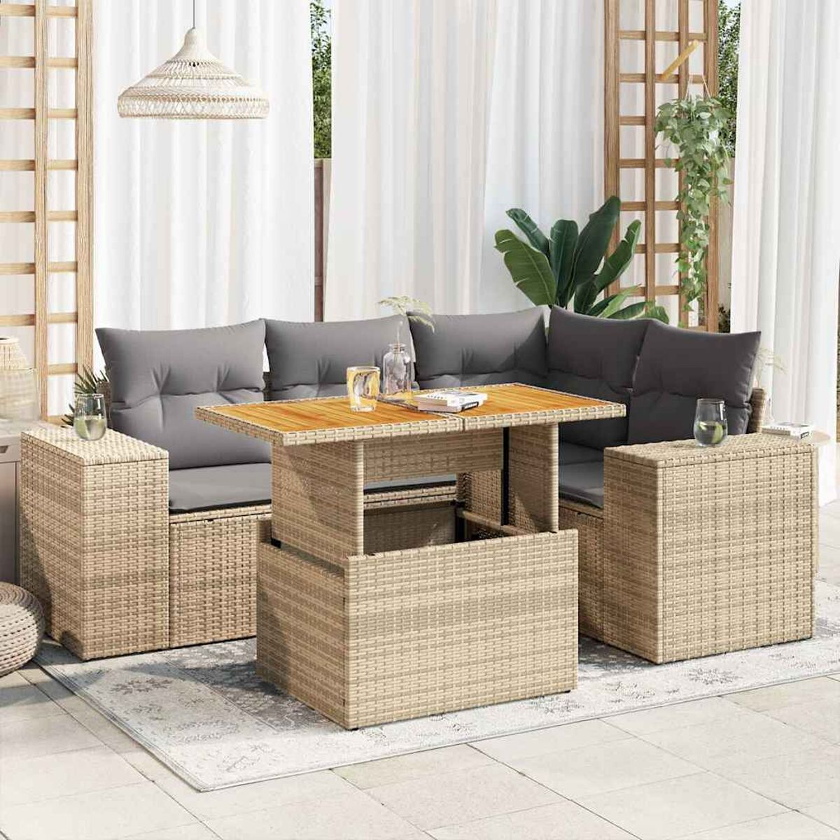 Un divano componibile in rattan per esterni con un tavolo sollevabile e due tavolini, su un patio.