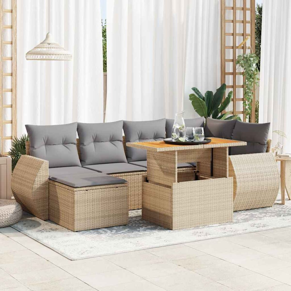 Beiges Rattan-Sofaset mit Tisch. Das Set hat graue Kissen und steht auf einer Terrasse.