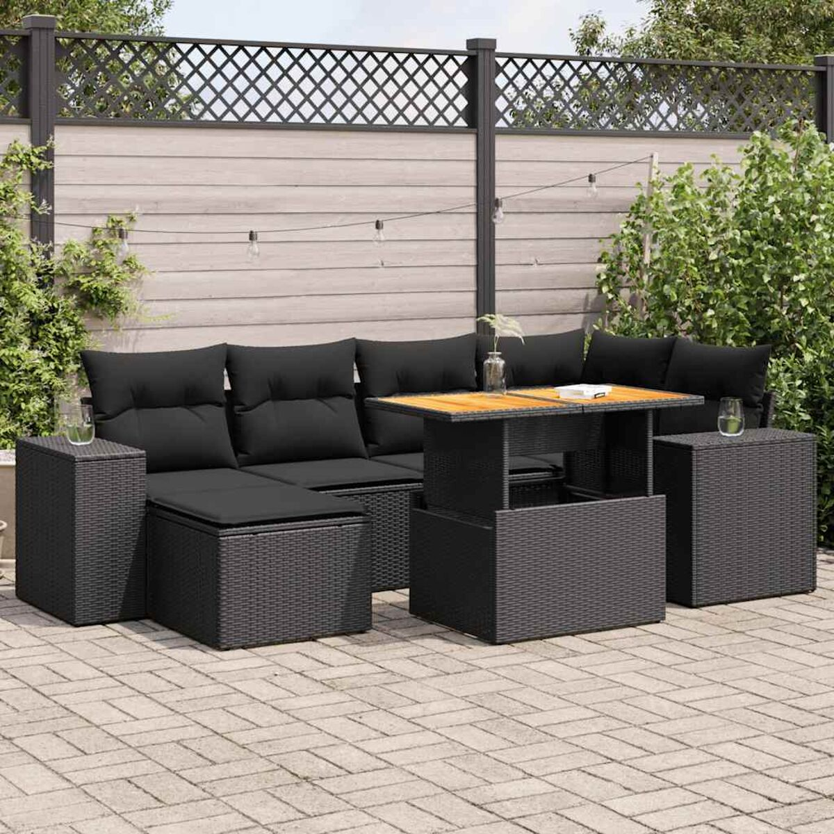 Set di mobili da esterno: divano nero, tavolo e due tavolini sul patio. Cuscini neri, telai grigio scuro.