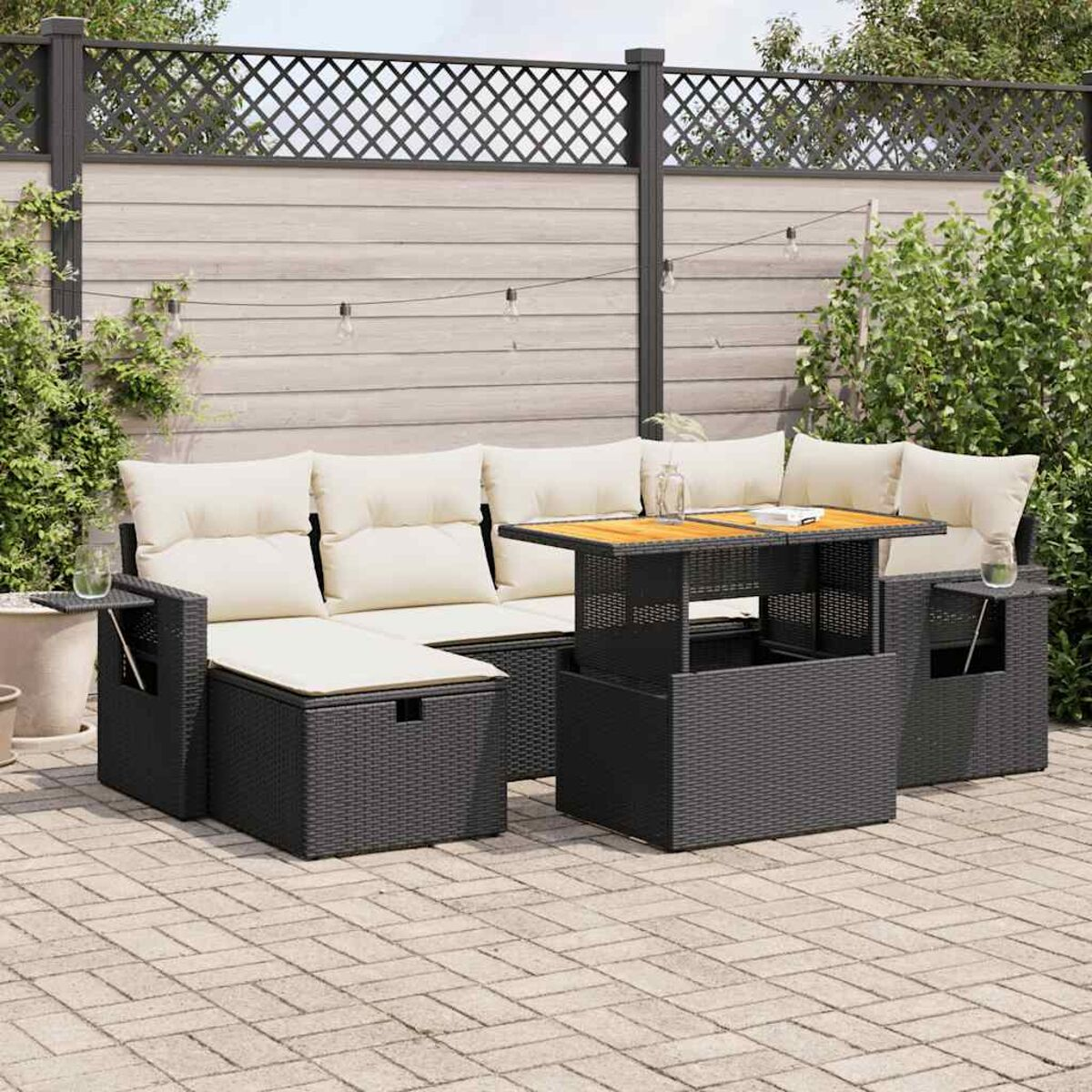 Schwarzes Rattan-Outdoor-Sofa mit cremefarbenen Kissen und Tisch mit Holzplatte. Szene ist eine Terrasse.