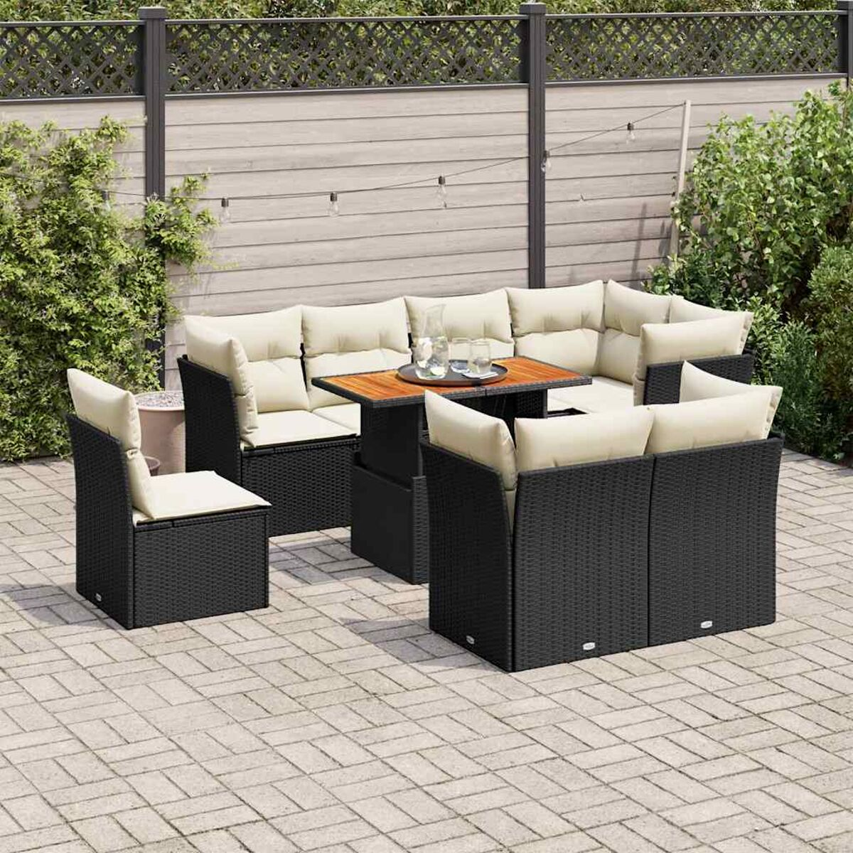 Set di mobili da esterno in vimini nero. Include divano, sedie, tavolo e cuscini.