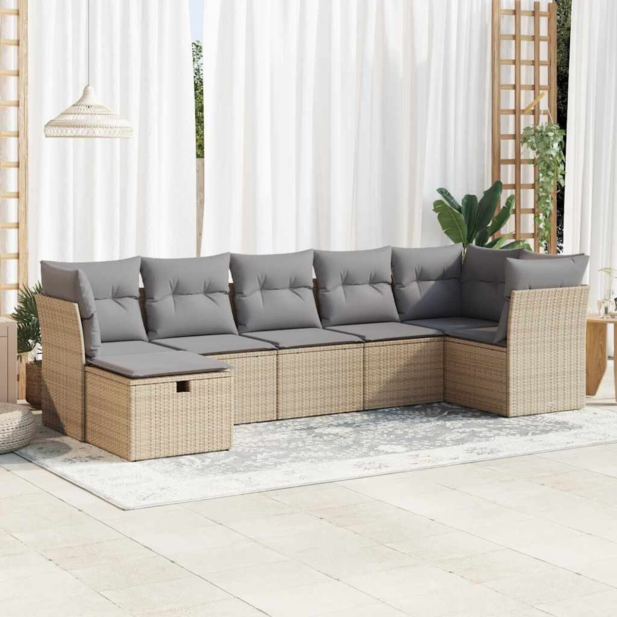 Un set di divani in vimini da esterno su un patio con cuscini e un tappeto.