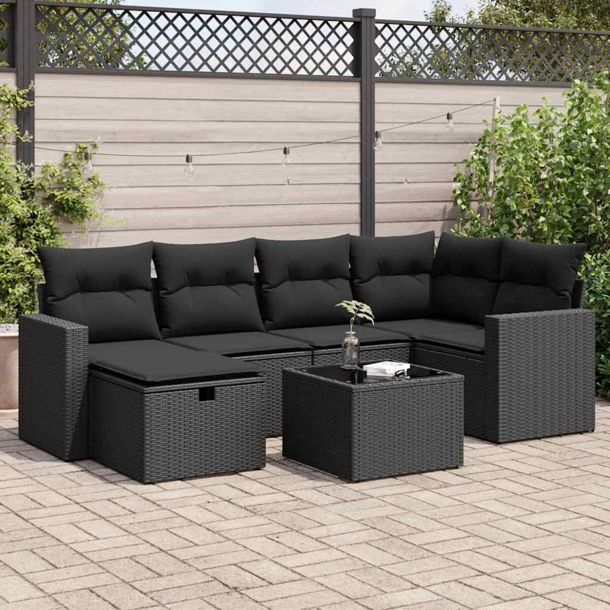 Un set da patio all'aperto con divano componibile nero e tavolino, su un patio in mattoni.