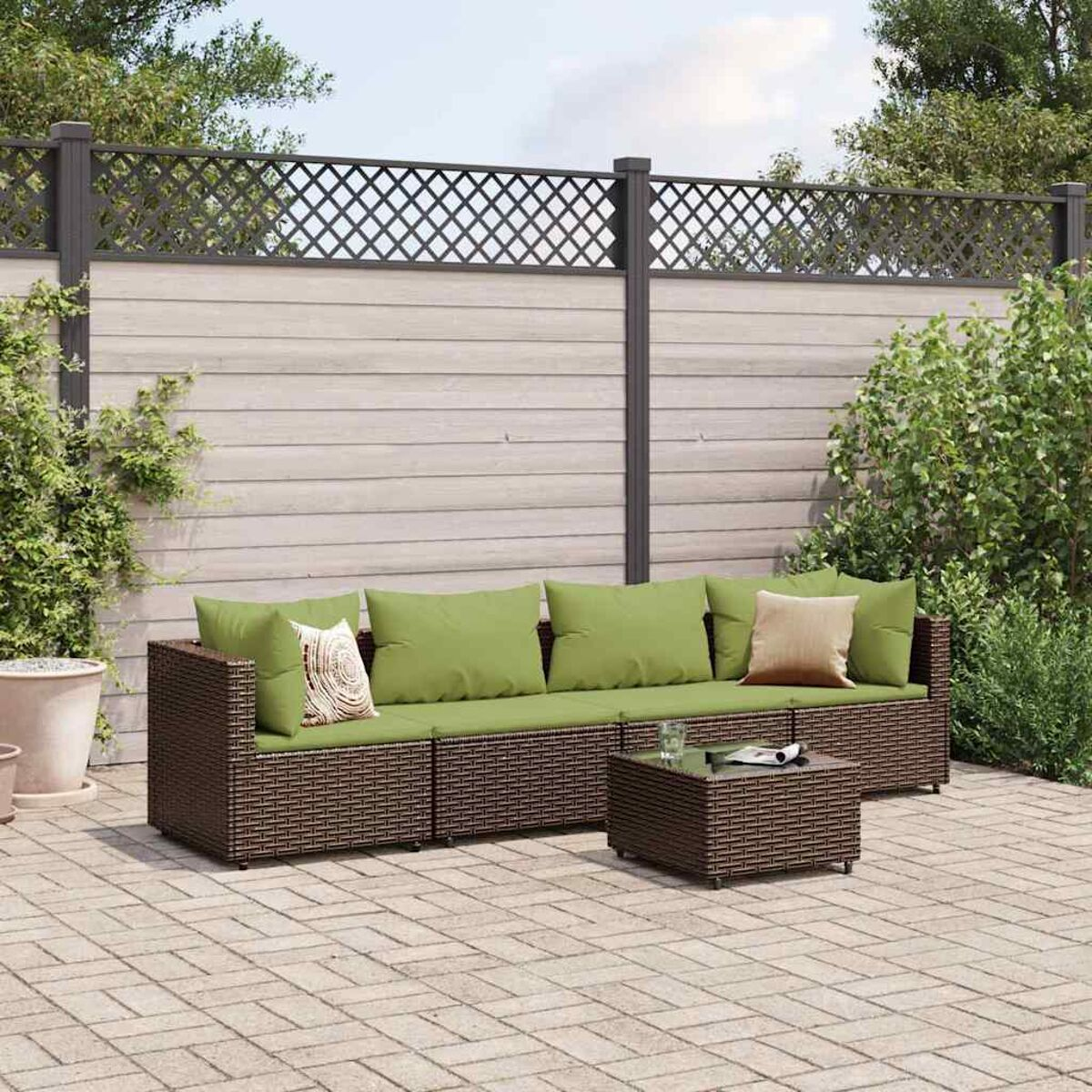 Set divano in rattan da esterno con cuscini verdi e tavolino.