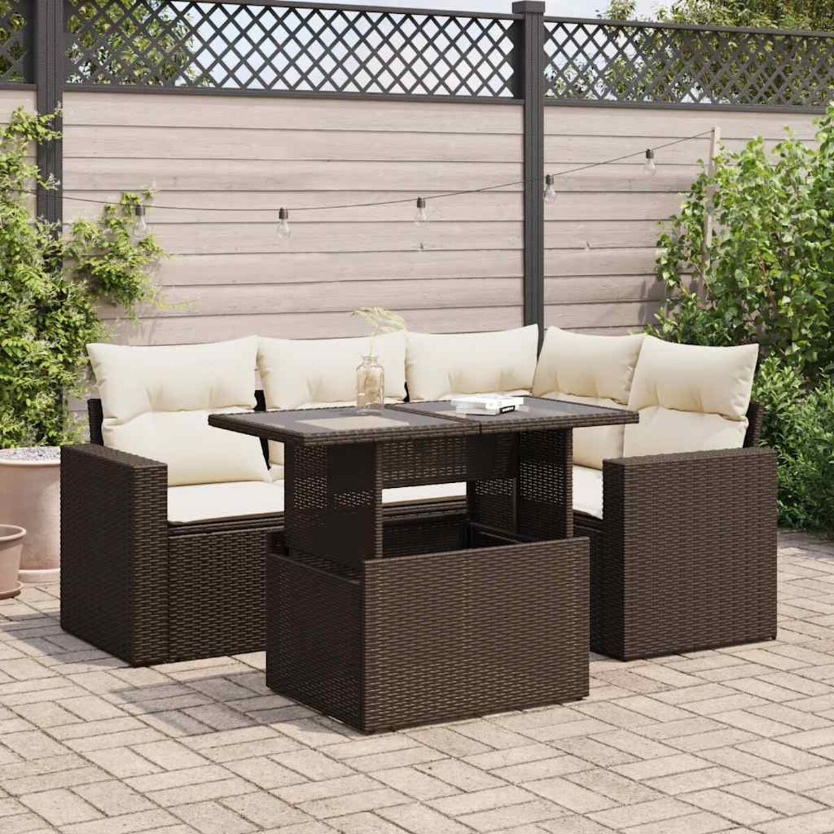 Set da esterno in vimini marrone: un divano, due sedie e un tavolo sollevabile con cuscini color crema.