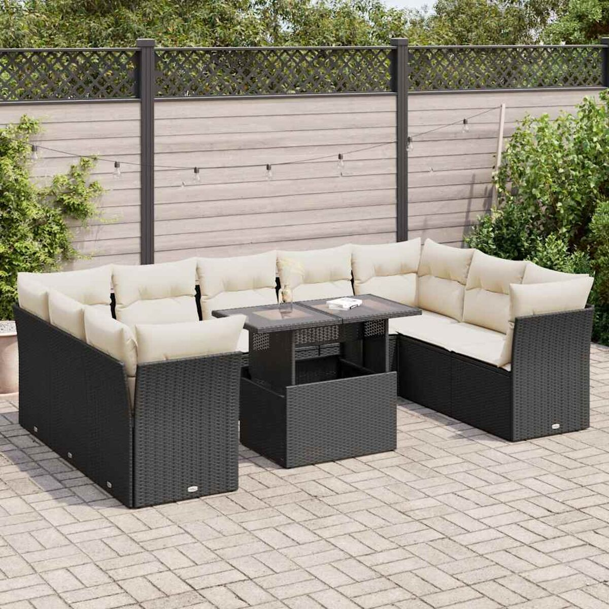 Un set di divani componibili da esterno in vimini nero con tavolino con piano in vetro e cuscini beige.