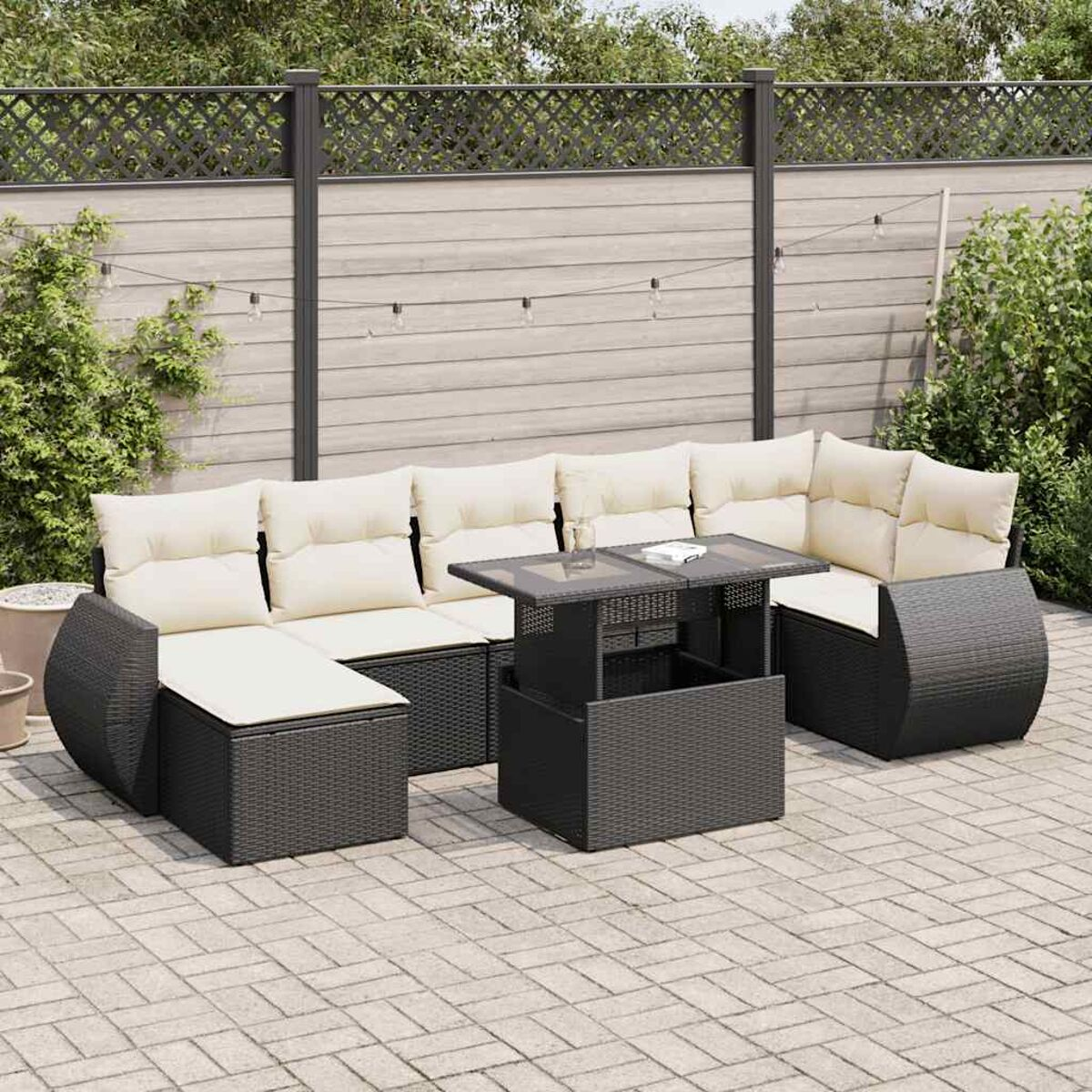 Set da patio con mobili in rattan scuro. Include divano, tavolo e sedie. Cuscini colorati chiari.