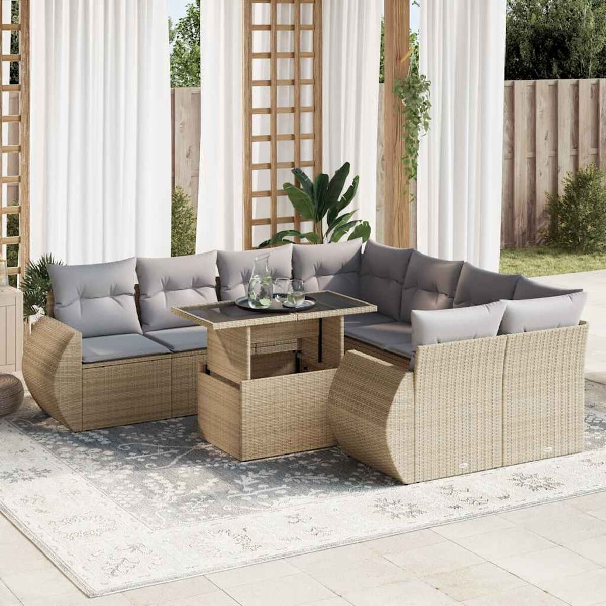 Set di mobili in rattan per esterni con tavolo e sedute. Tende bianche.