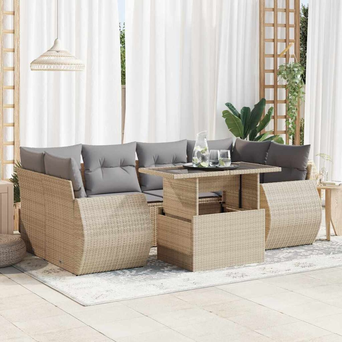 Set divano in rattan da esterno con tavolo elevabile, cuscini e decorazioni.