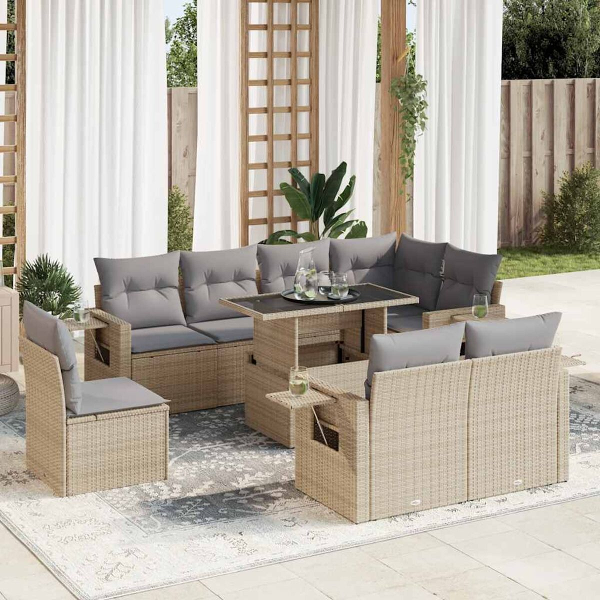 Set di mobili da esterno in rattan con tavolo, divani e sedie su un tappeto fantasia.