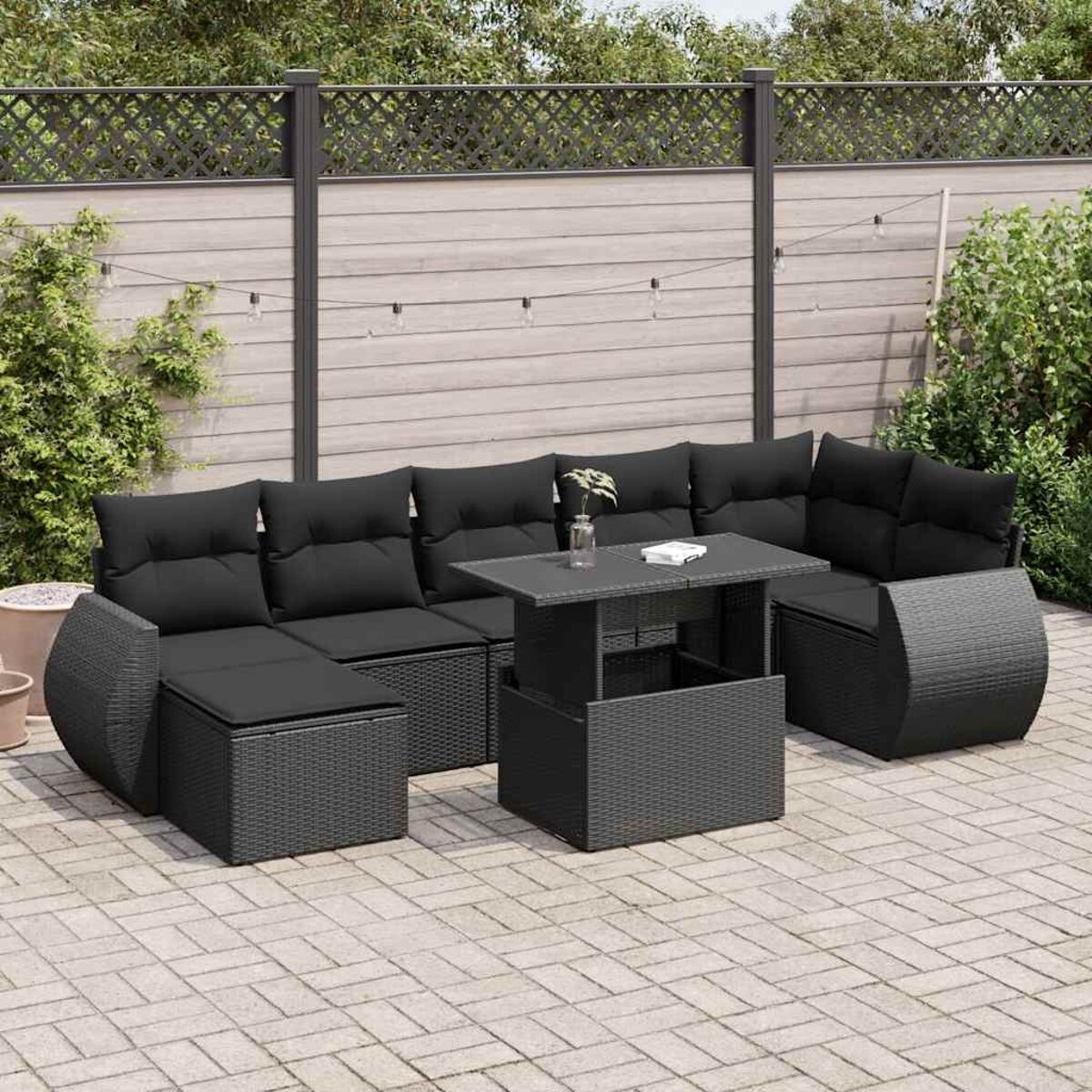 Set di sedute per esterni nero con tavolo con piano sollevabile. Su patio in mattoni con recinzione.