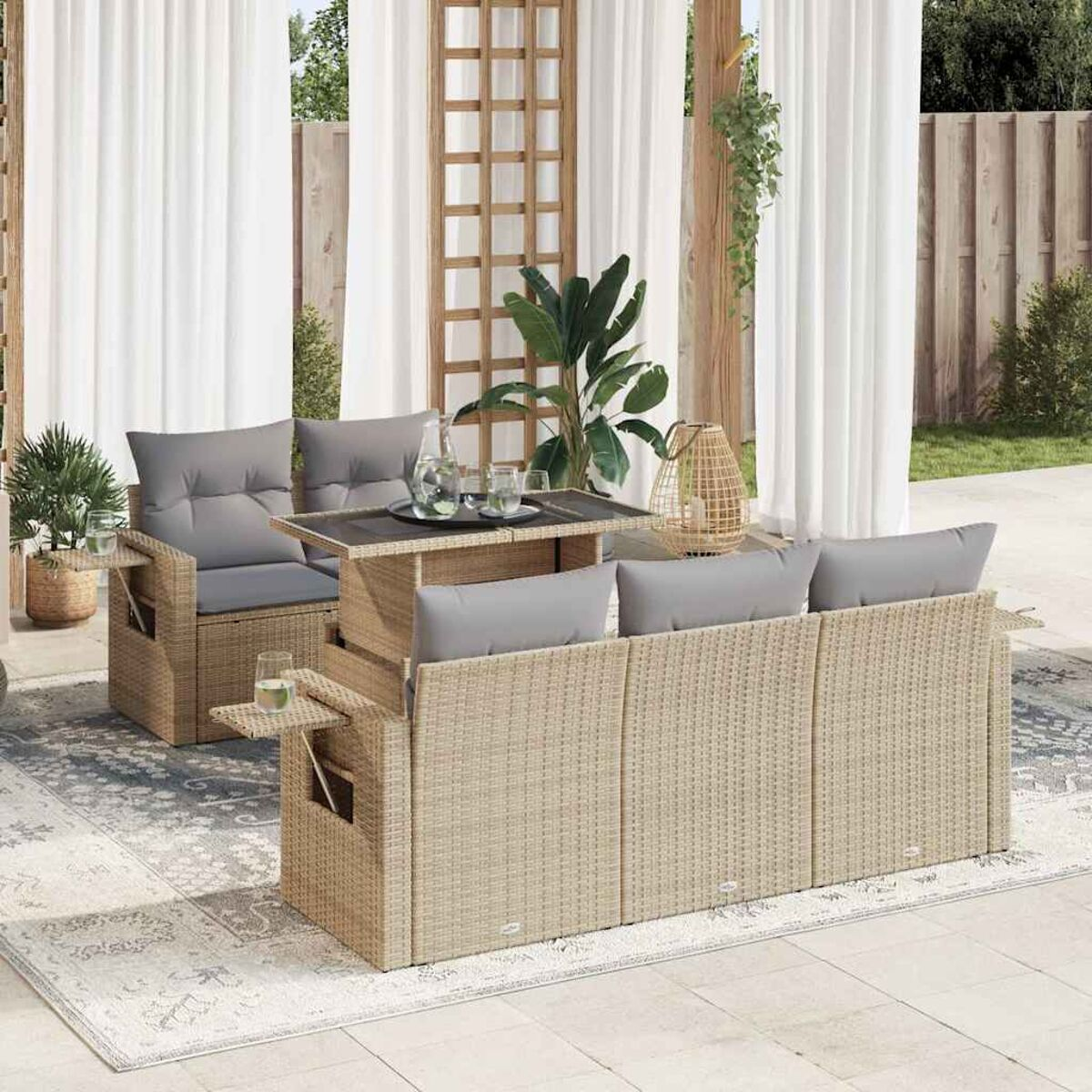 Beiges Outdoor-Sofaset aus Korbgeflecht mit grauen Kissen, Tisch und Sessel auf einer Terrasse.