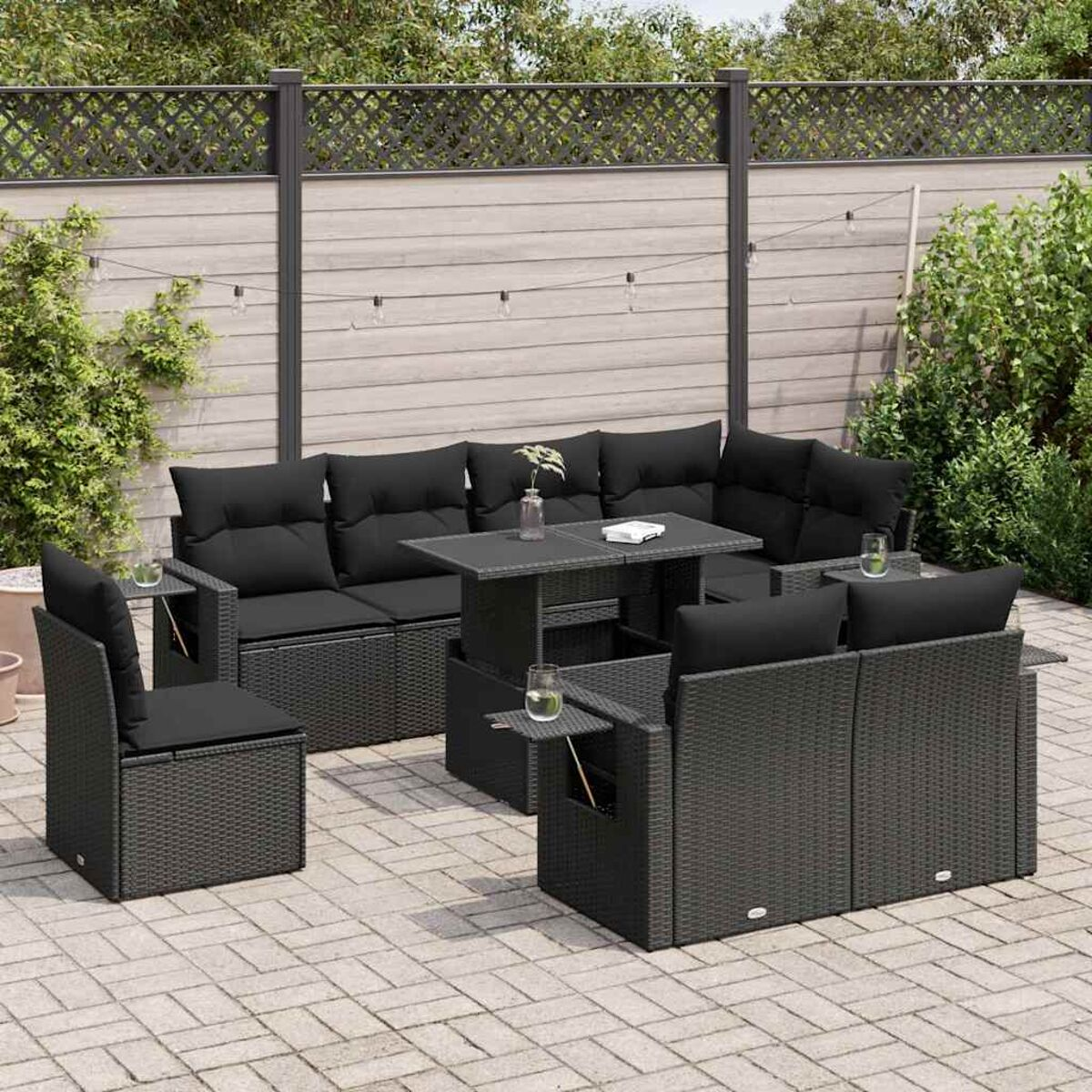 Set di mobili da esterno in rattan nero con tavolo e cuscini su un patio.