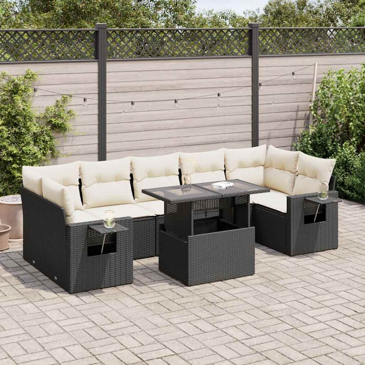 Un set di mobili da esterno in rattan nero con tavolo e cuscini color crema.