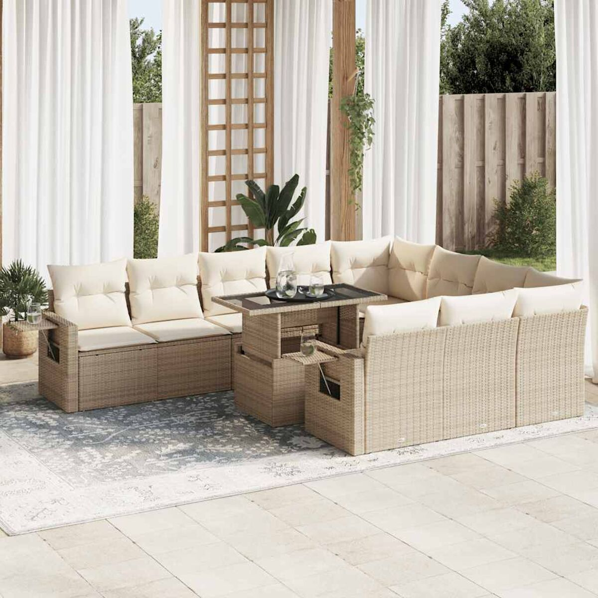 Divano componibile beige da esterno con cuscini, tavolo e tende. Su un patio pavimentato grigio chiaro.