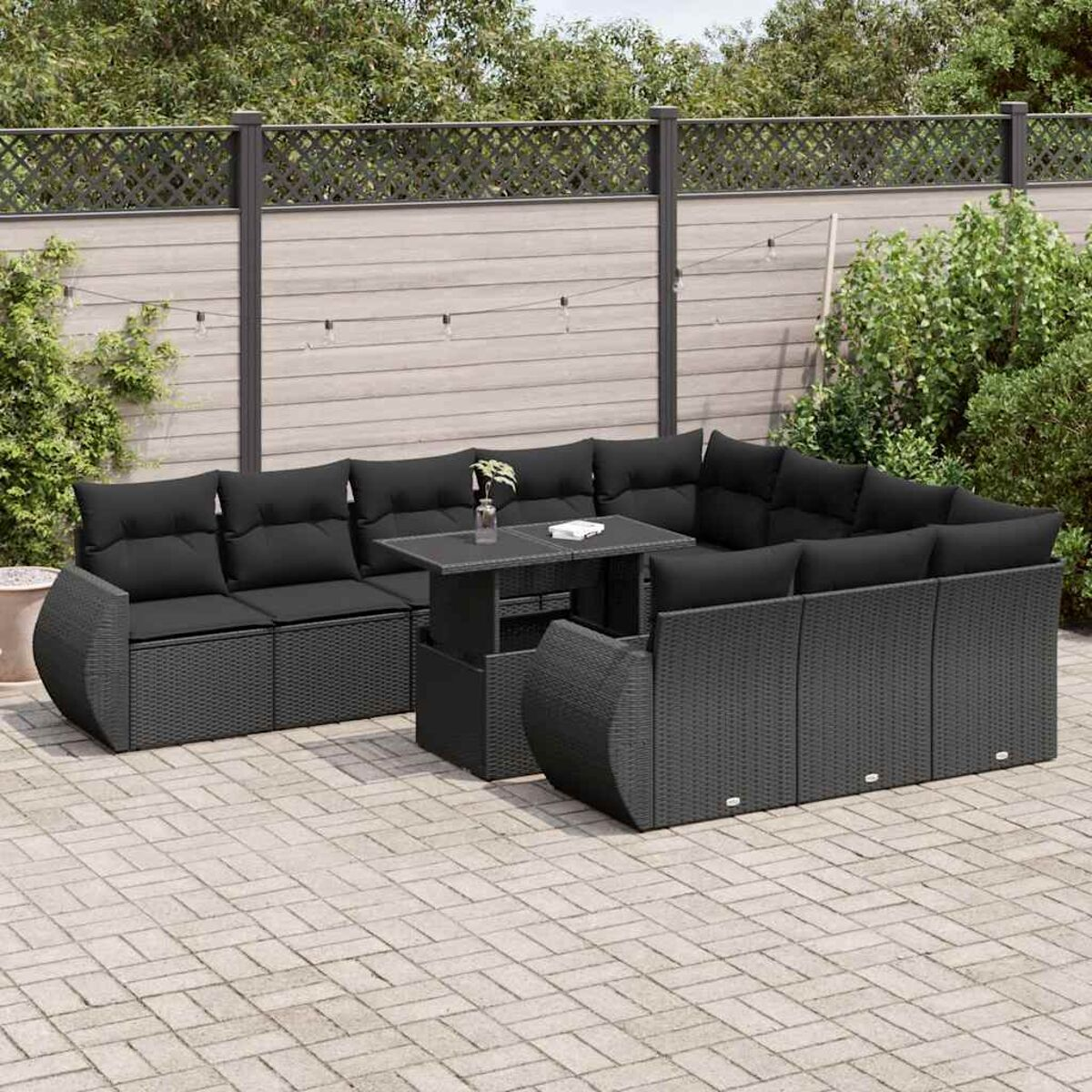 Divano angolare in rattan nero con cuscini neri e tavolo su un patio.