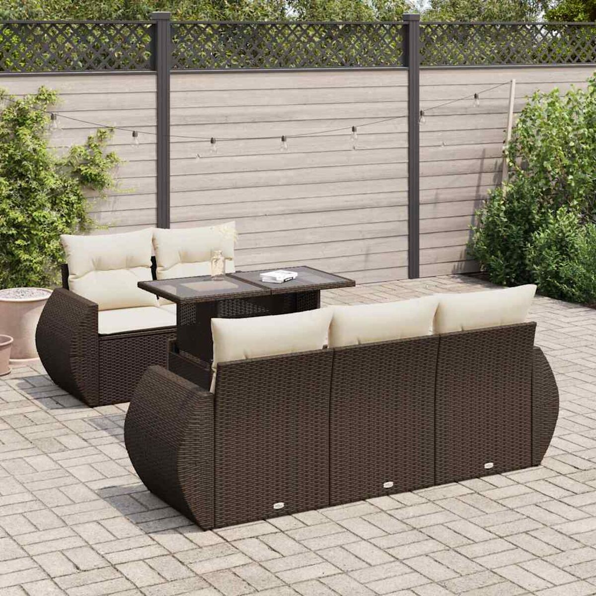 Geflochtener Sitzbereich im Freien mit Sofa, Tisch und Stuhl. Inklusive Kissen und gepflasterter Terrasse.
