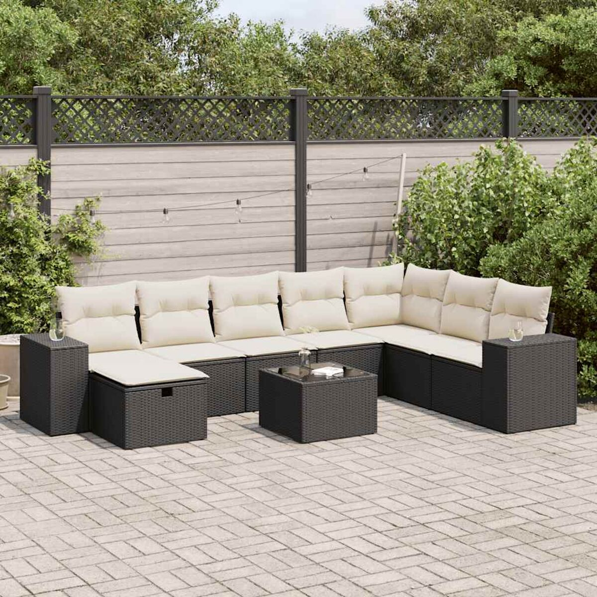 Dunkelgraues Outdoor-Ecksofa mit beigefarbenen Kissen auf einer Backstein-Terrasse.