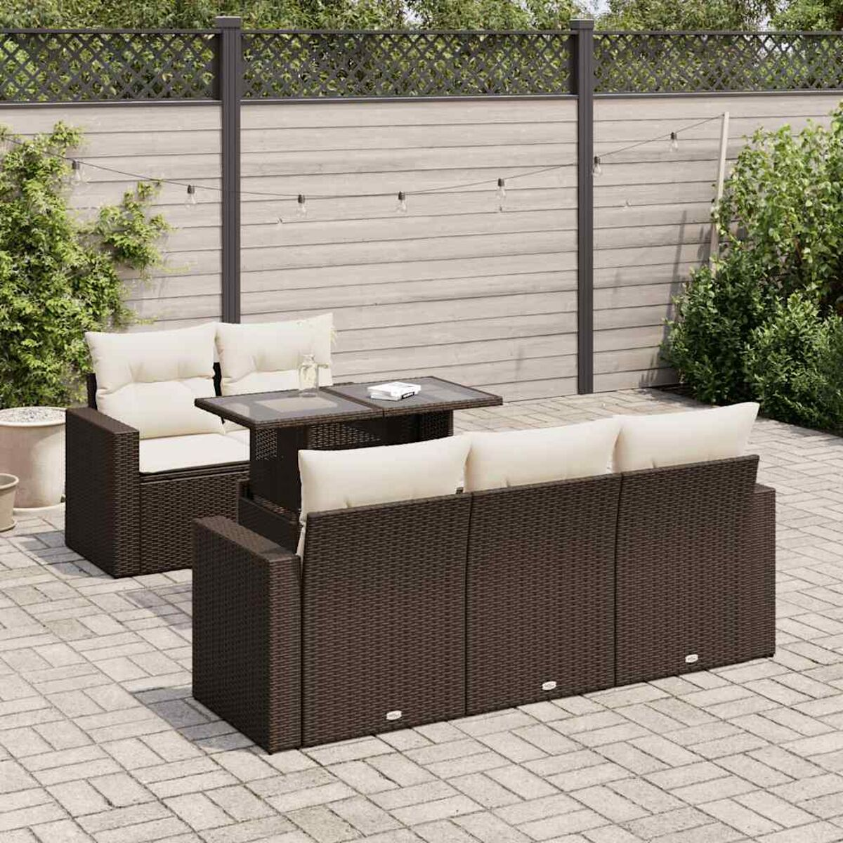 Braunes Outdoor-Möbelset aus Korbgeflecht mit Tisch und beigen Kissen. Hintergrundzaun.