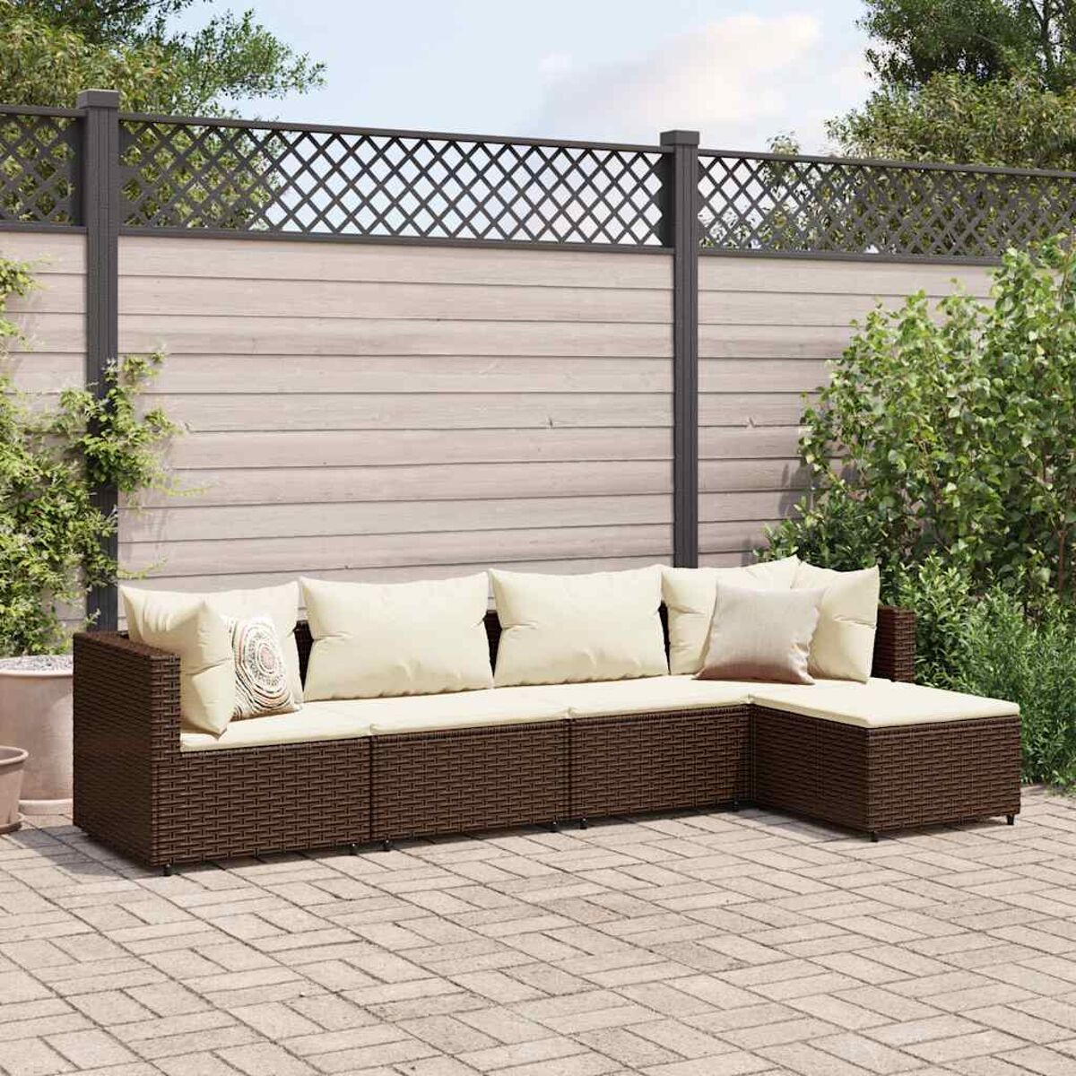 Divano componibile da esterno in rattan marrone con cuscini beige, su un patio in mattoni.