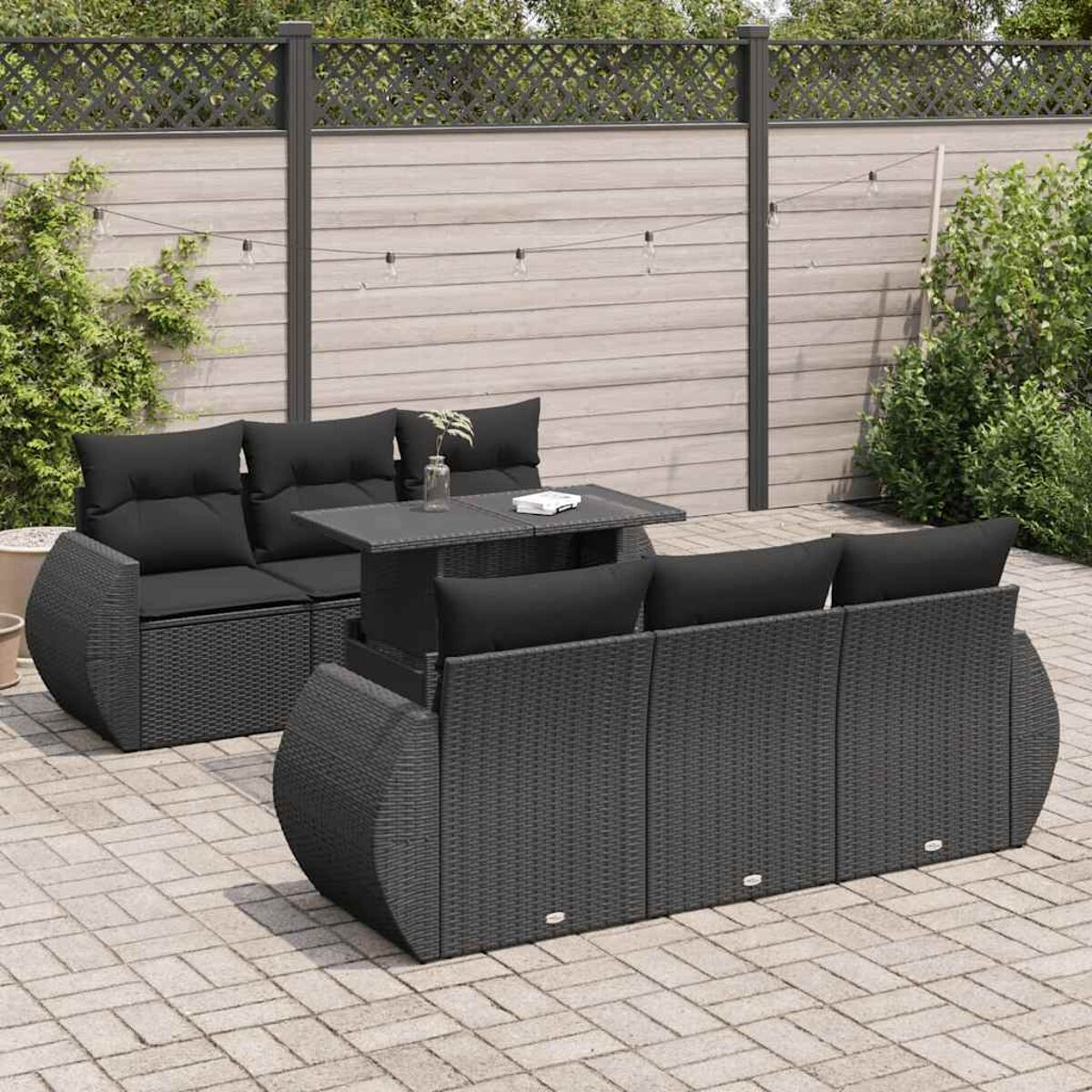 Set di sedute da esterno in vimini nero con cuscini neri e tavolo.