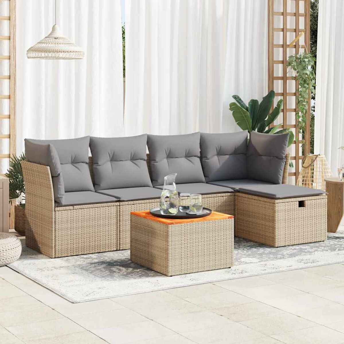 Beiges Outdoor-Ecksofa mit grauen Kissen und einem Tisch auf einem Teppich. Weiße Vorhänge und Pflanzen im Hintergrund.