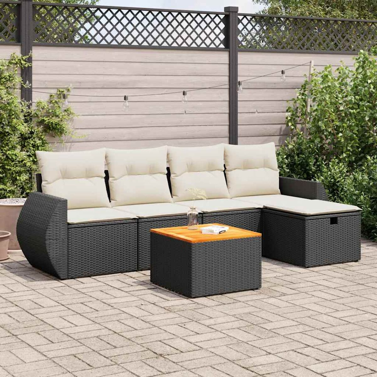 Outdoor-Ecksofa mit cremefarbenen Kissen, einem Tisch und einer Terrasse mit Grün und einem Zaun.