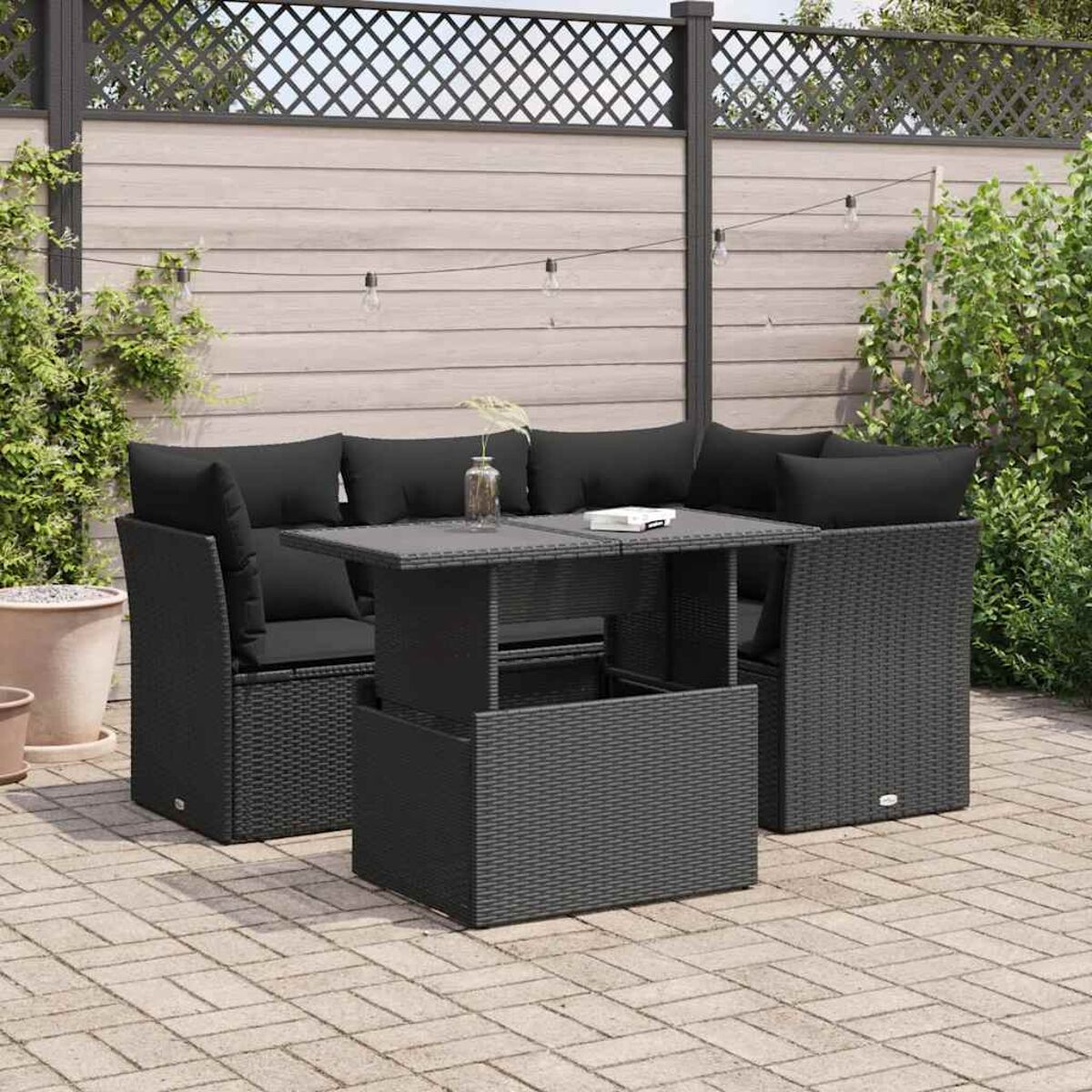 Schwarzes Sitzmöbel-Set für den Außenbereich aus Korbgeflecht. Ein Tisch in der Mitte. Schwarze Kissen. Dunkelgraue Terrasse.