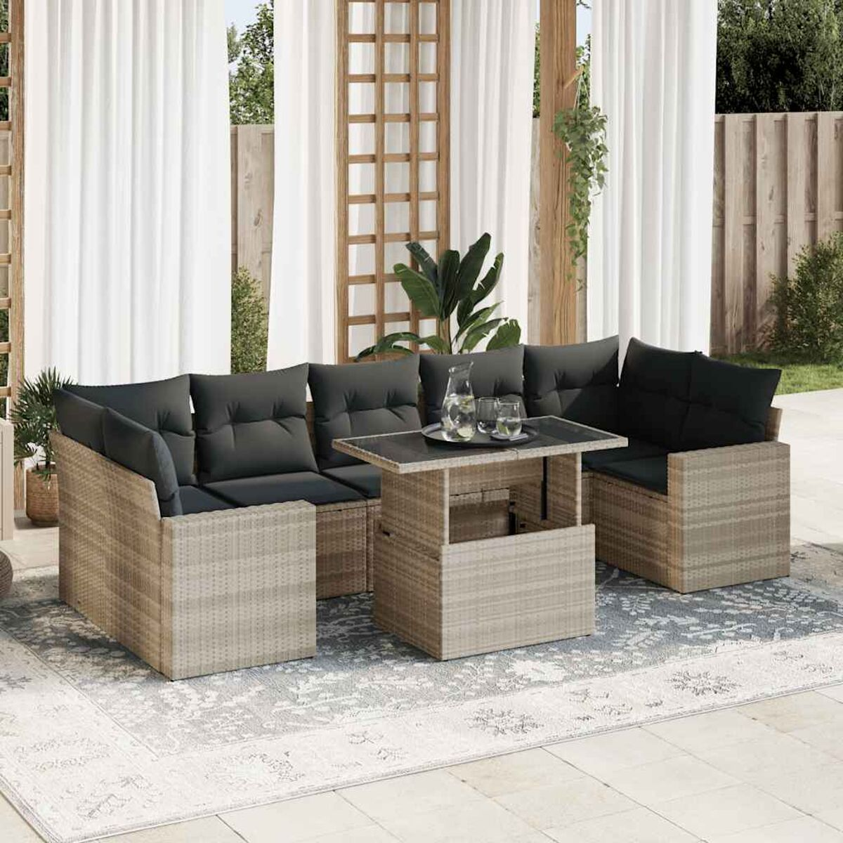 Rattan-Outdoor-Sofagarnitur mit Kissen, Tisch und Glas, neben Vorhängen.
