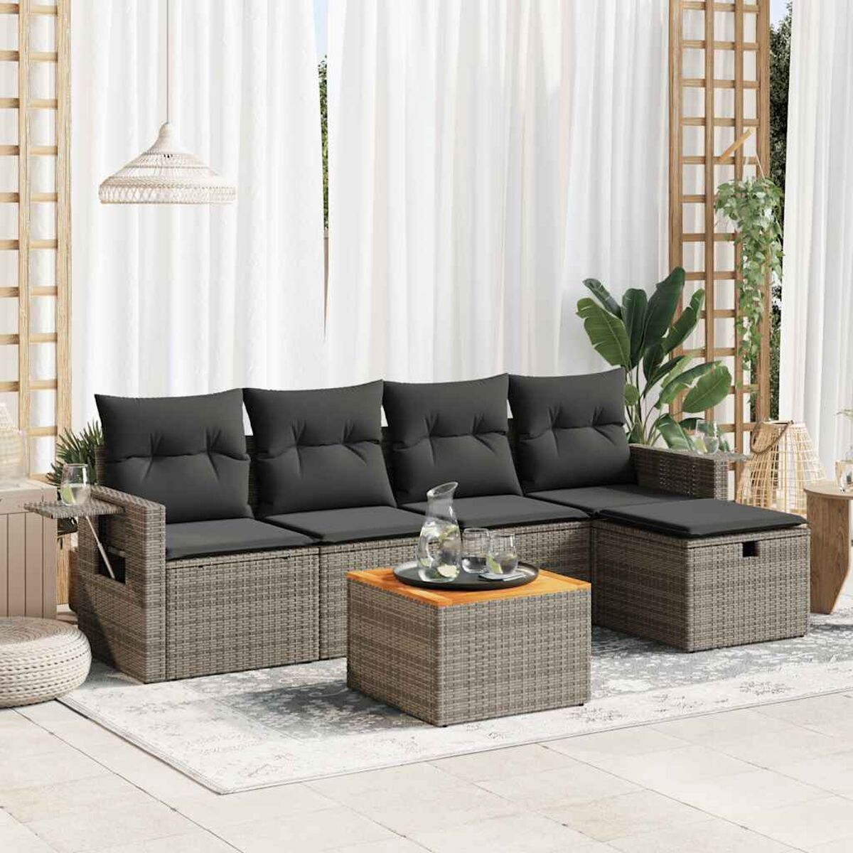 Sofá seccional de ratán gris para exteriores con cojines negros y mesa de madera.