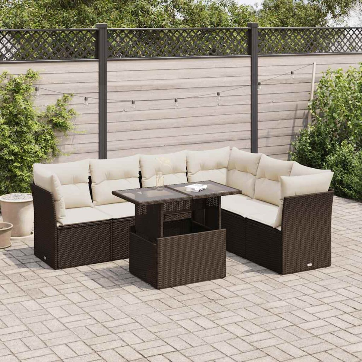 Outdoor-Ecksofa aus Korbgeflecht mit beigen Kissen und einem Tisch mit Hubfunktion auf einer Ziegelterrasse.